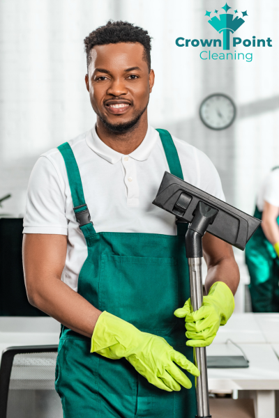 Male cleaner standing in commercial space, smiling at the camera while on a janitorial job for Crown Point Cleaning.